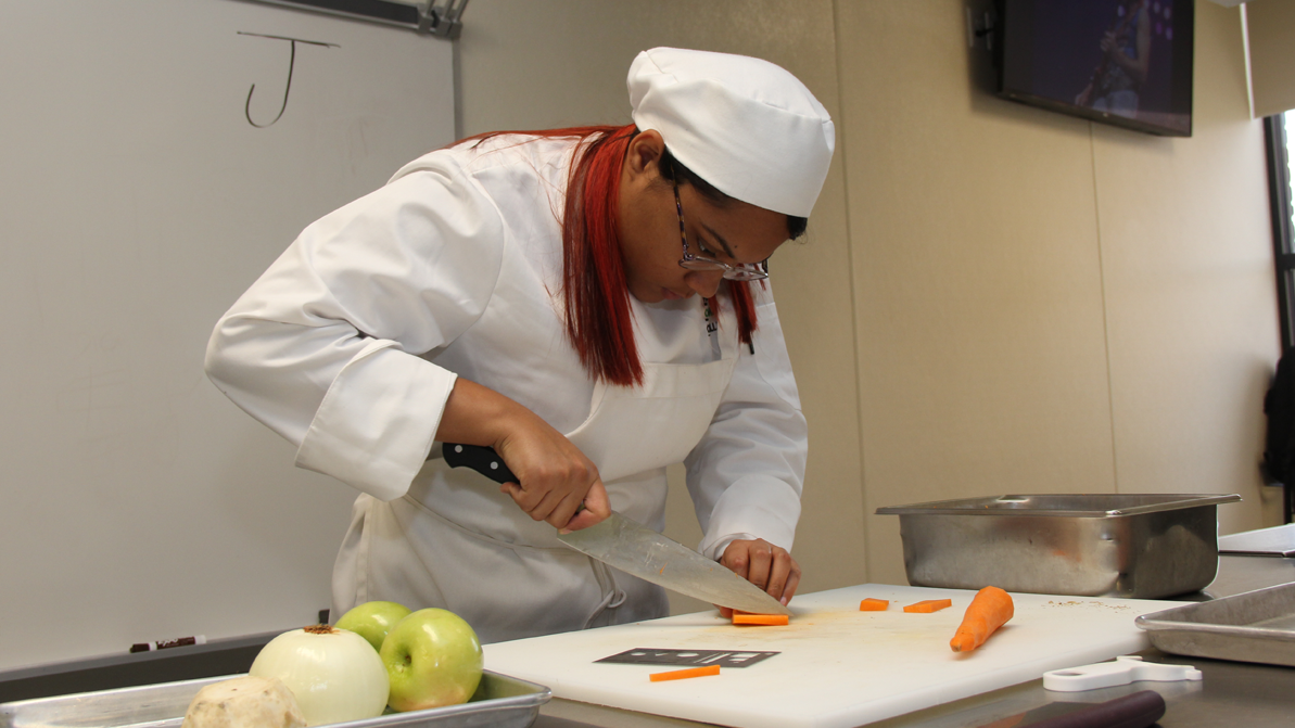 A culinary arts student chops carrots in the HCC MGM Culinary Arts Institute